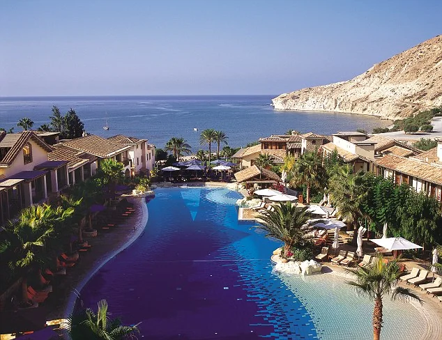 Resort swimming pool and gardens overlooking the sea and cliffs at Pissouri, Cyprus.