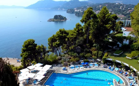 Swimming pool and wooded coastline overlooking the bay in Corfu, Greece.