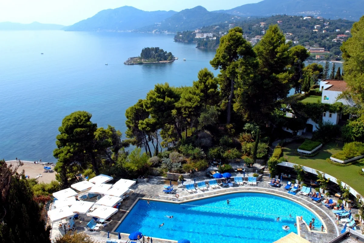 Swimming pool and wooded coastline overlooking the bay in Corfu, Greece.