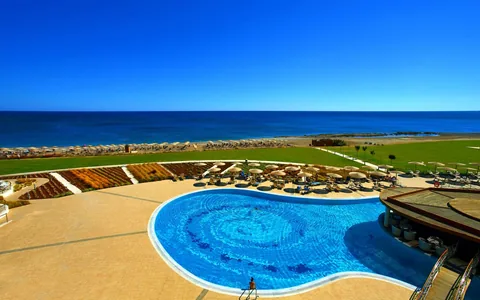 Curved swimming pool and sun terraces overlooking the sea at Elysium Resort and Spa, Rhodes.