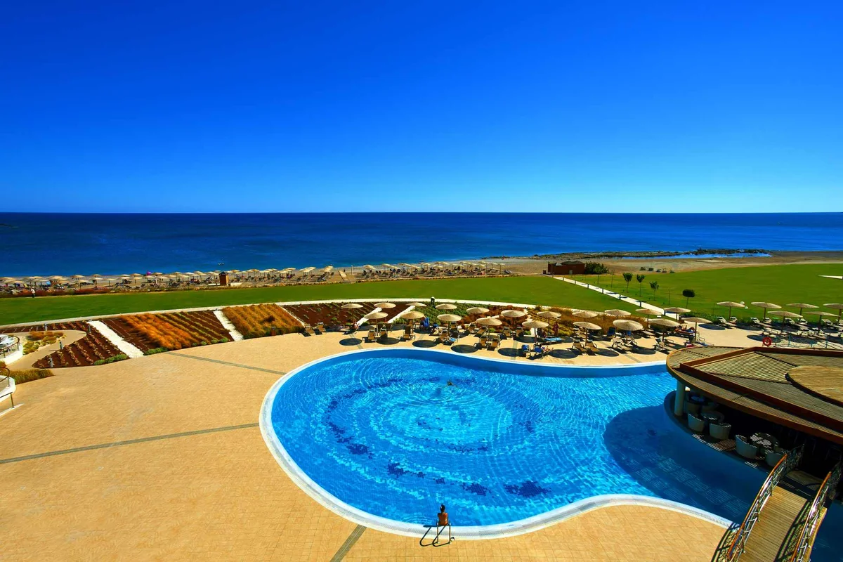 Curved swimming pool and sun terraces overlooking the sea at Elysium Resort and Spa, Rhodes.