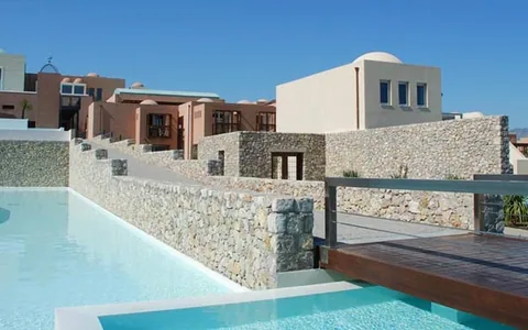 Pale stone resort buildings and a bridge beside a pool at Helona Resort, Kos.