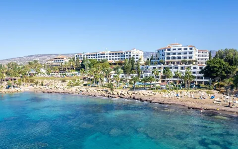 Coral Beach Resort beside a rocky shoreline and clear blue water in Paphos, Cyprus.