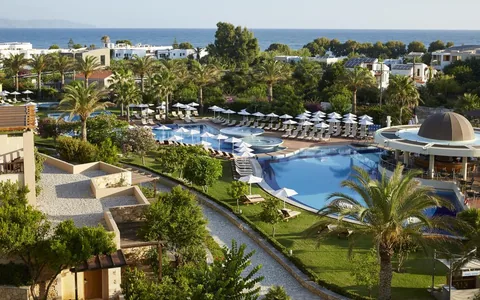Swimming pools, palms and gardens at Minoa Palace Resort with the sea beyond.